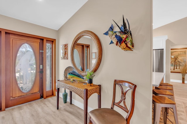 foyer entrance with vaulted ceiling and light hardwood / wood-style flooring