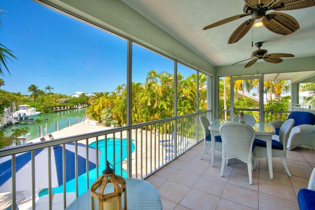 sunroom with a water view and ceiling fan