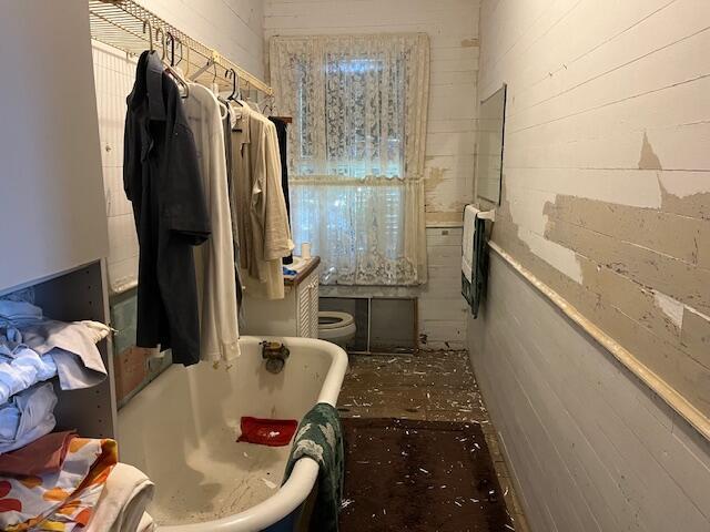 bathroom with a tub, heating unit, and wooden walls