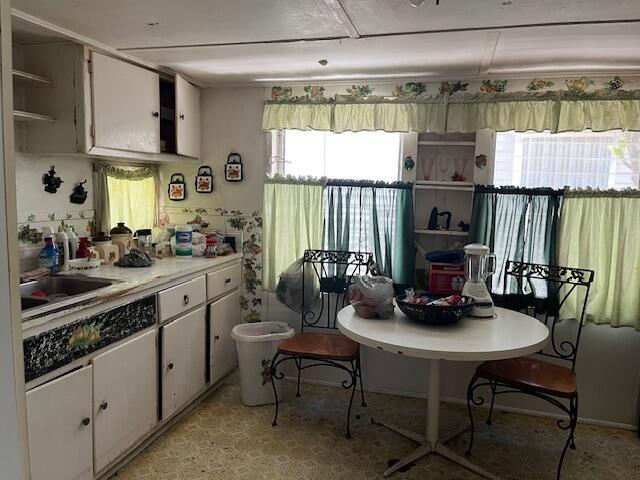 kitchen with white cabinets, open shelves, light countertops, and a sink