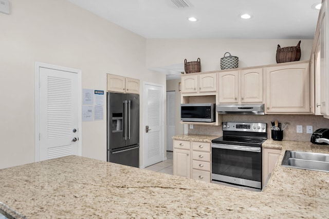 kitchen with lofted ceiling, sink, light tile patterned floors, stainless steel appliances, and cream cabinets