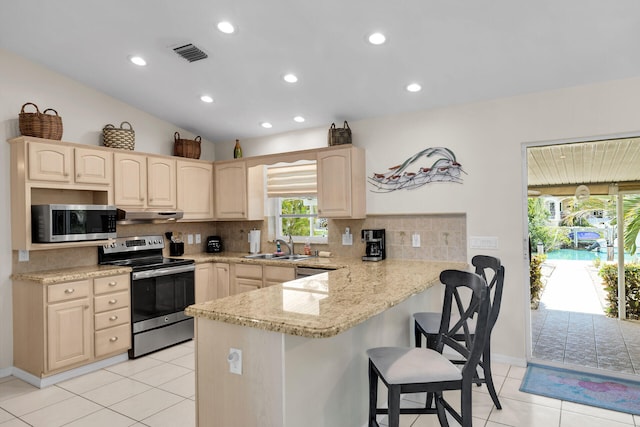 kitchen with appliances with stainless steel finishes, sink, backsplash, kitchen peninsula, and light stone countertops