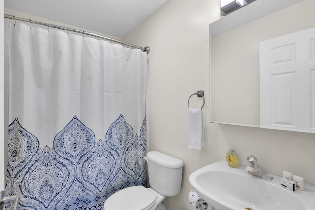 bathroom with toilet, curtained shower, and sink