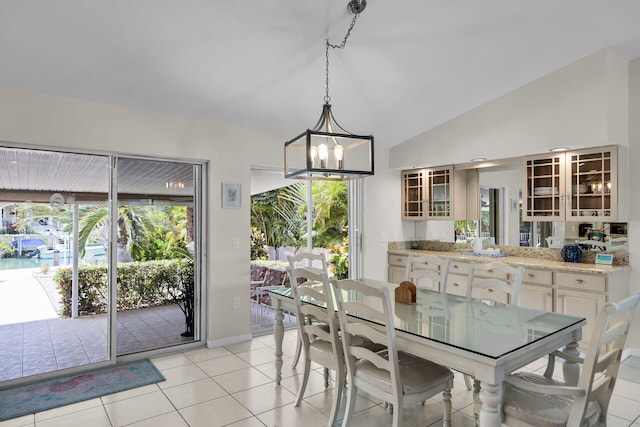 tiled dining room with a notable chandelier and vaulted ceiling