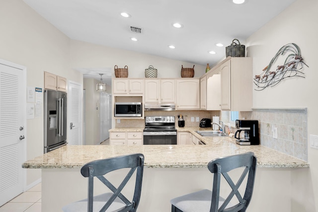 kitchen with sink, tasteful backsplash, a kitchen breakfast bar, kitchen peninsula, and stainless steel appliances