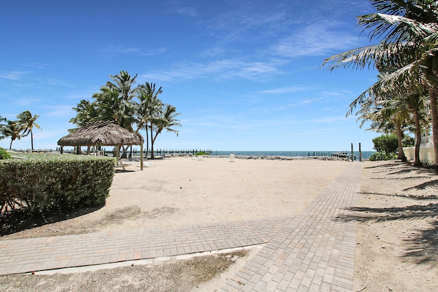 surrounding community with a gazebo, a water view, and a view of the beach