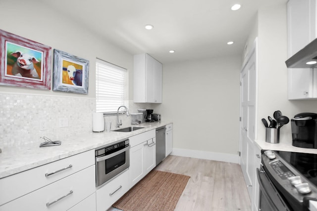 kitchen with sink, light stone counters, appliances with stainless steel finishes, light hardwood / wood-style floors, and white cabinets