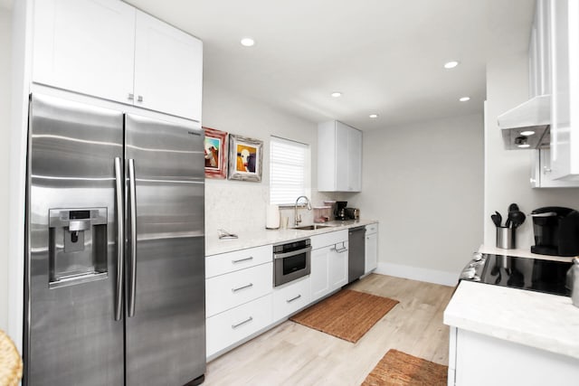 kitchen with white cabinetry, sink, light stone counters, and stainless steel appliances