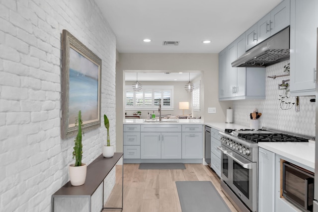 122 S Bay Harbor Dr, Key Largo, FL 33037 - kitchen featuring appliances with stainless steel finishes, under cabinet range hood, light wood-style flooring, light countertops, and a sink