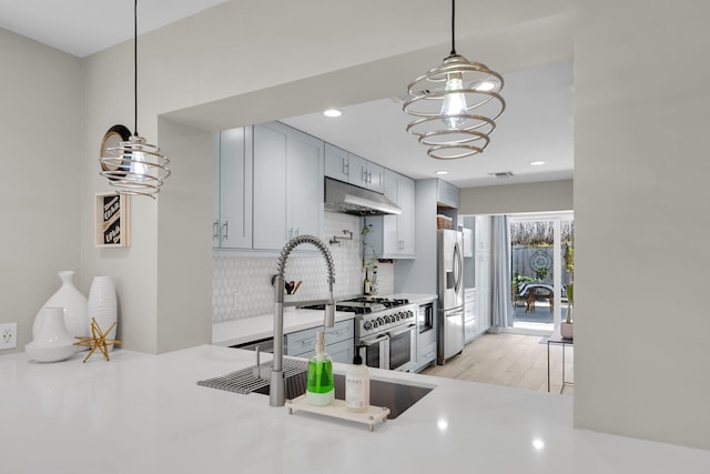 122 S Bay Harbor Dr, Key Largo, FL 33037 - kitchen featuring appliances with stainless steel finishes, under cabinet range hood, tasteful backsplash, a chandelier, and light countertops