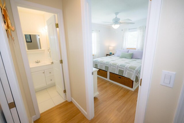 bedroom with ensuite bath, sink, and light hardwood / wood-style flooring