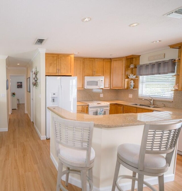 kitchen with light hardwood / wood-style floors, sink, white appliances, and kitchen peninsula