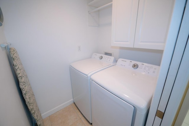 laundry area with light tile patterned floors, washer and clothes dryer, and cabinets