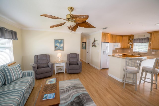 living room featuring sink, crown molding, light hardwood / wood-style flooring, and ceiling fan