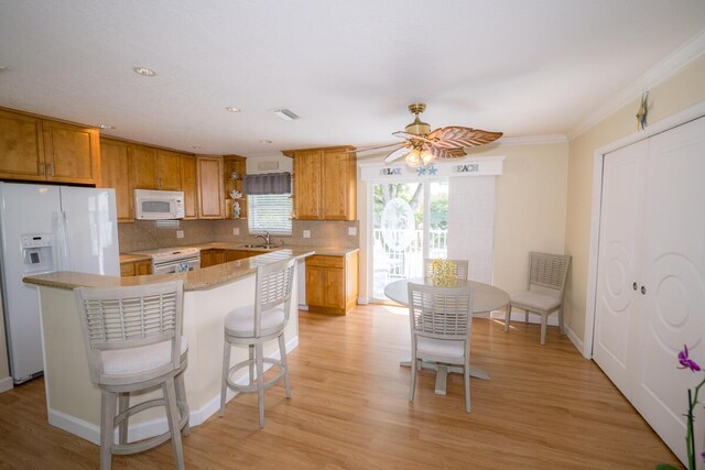 kitchen with crown molding, light wood-type flooring, white appliances, and decorative backsplash