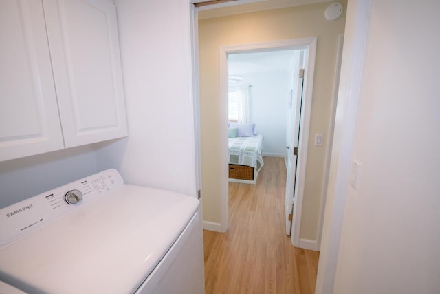 laundry area featuring washer / clothes dryer, cabinets, and light hardwood / wood-style flooring