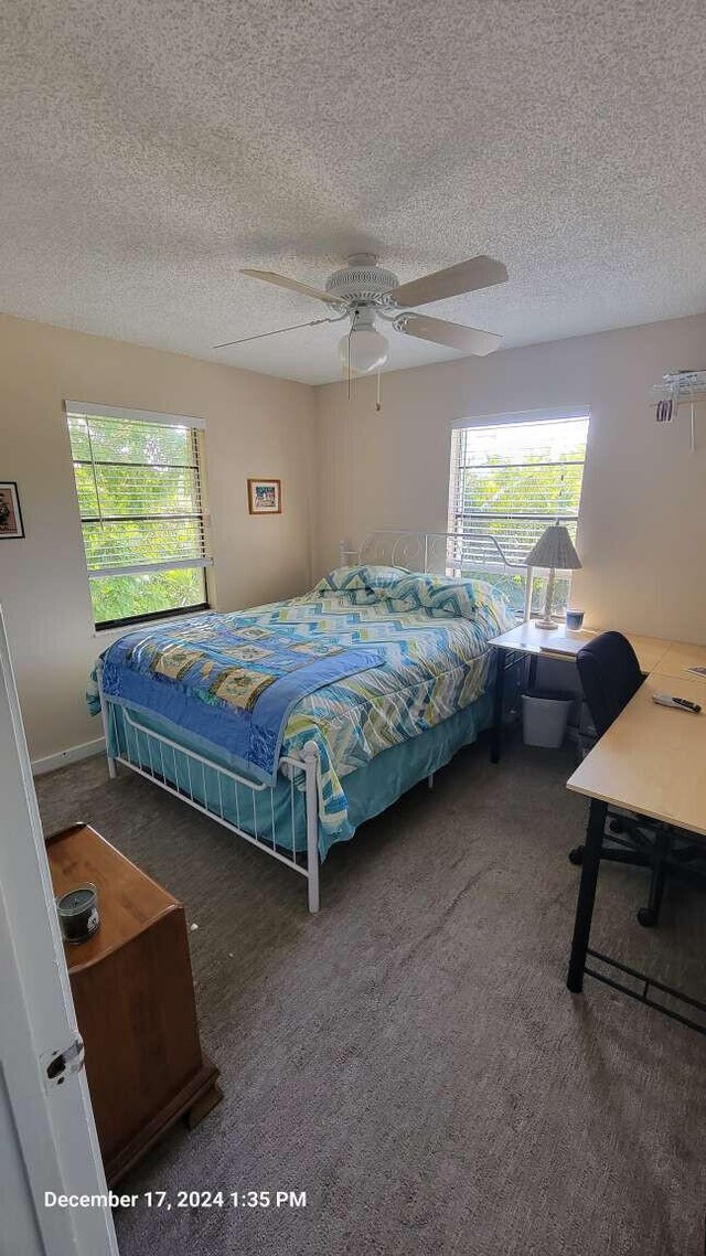 bedroom featuring a textured ceiling, ceiling fan, and dark colored carpet