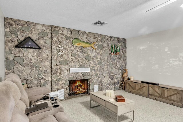 living room with a stone fireplace and a textured ceiling