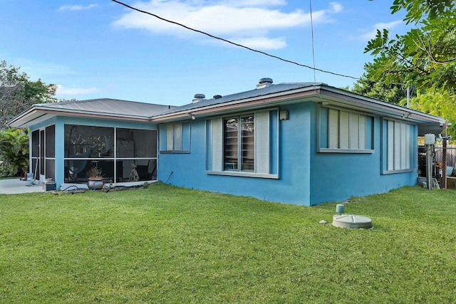 rear view of property featuring a lawn and a sunroom