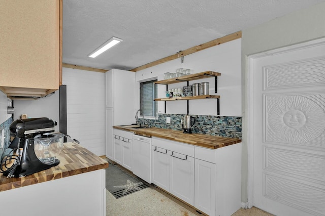 kitchen with wood counters, dishwasher, sink, white cabinets, and a textured ceiling