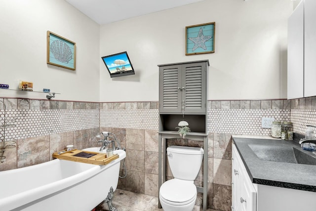 bathroom with vanity, a tub, tile walls, and toilet