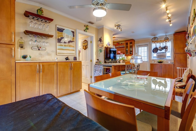 tiled dining space with track lighting, ornamental molding, beverage cooler, and bar