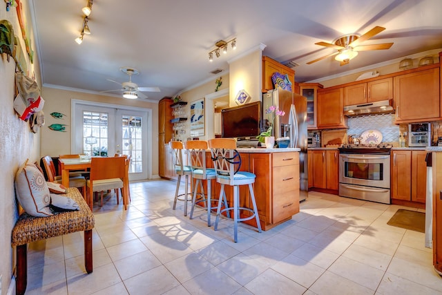 kitchen featuring light tile patterned floors, a breakfast bar, stainless steel appliances, ornamental molding, and decorative backsplash