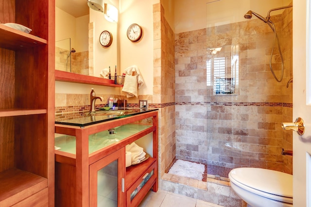 bathroom featuring tile patterned flooring, vanity, tiled shower, and toilet