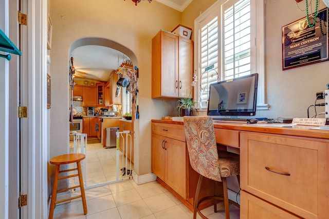 office space with crown molding, built in desk, light tile patterned flooring, and plenty of natural light