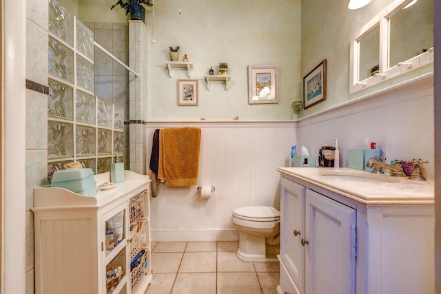 bathroom with tiled shower, tile patterned floors, toilet, and vanity