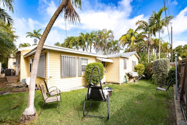 back of house featuring a yard and central air condition unit