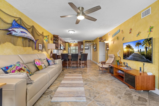 living room featuring ceiling fan and a textured ceiling