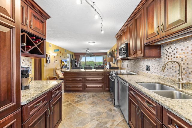 kitchen with sink, light stone counters, a textured ceiling, stainless steel appliances, and backsplash