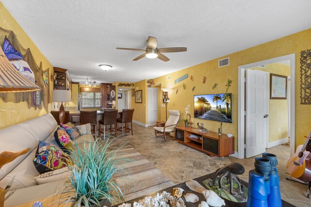 living room with ceiling fan and a textured ceiling