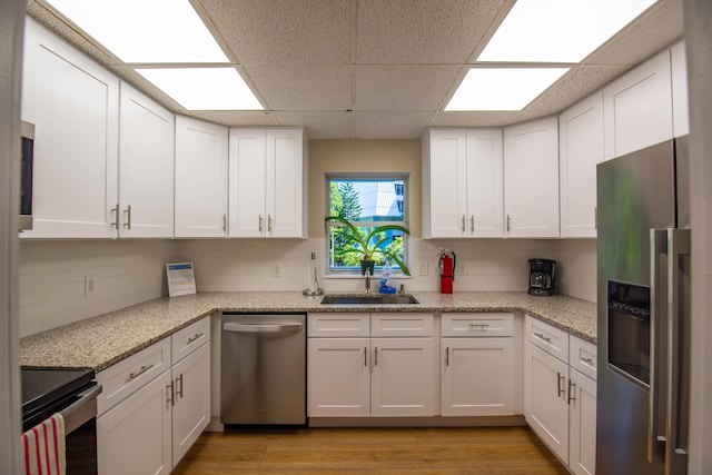 kitchen with white cabinetry, appliances with stainless steel finishes, sink, and light stone counters