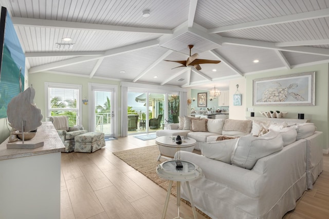 living room with ceiling fan with notable chandelier, light hardwood / wood-style floors, and lofted ceiling with beams