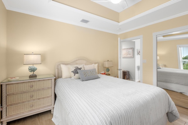 bedroom with a tray ceiling, ornamental molding, and light hardwood / wood-style floors