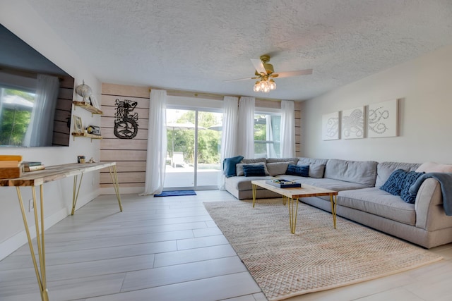 living room with ceiling fan, a textured ceiling, and light hardwood / wood-style flooring