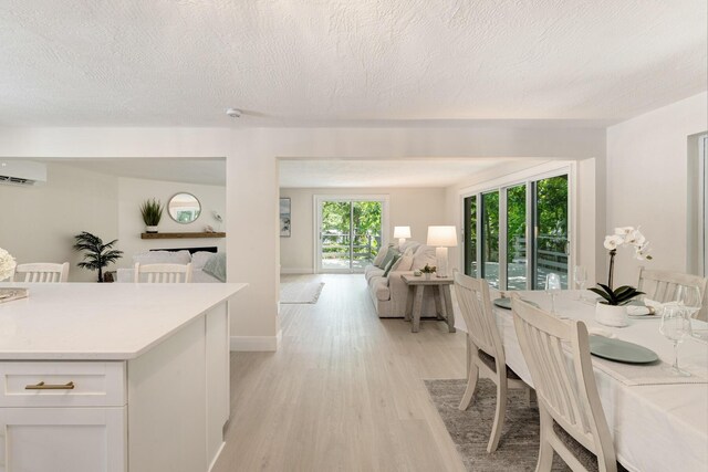 82260 Overseas Hwy, Islamorada, FL 33036 - dining room featuring an AC wall unit, light wood finished floors, and a textured ceiling
