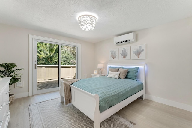 82260 Overseas Hwy, Islamorada, FL 33036 - bedroom with a wall unit AC, light wood-style floors, access to exterior, and a textured ceiling