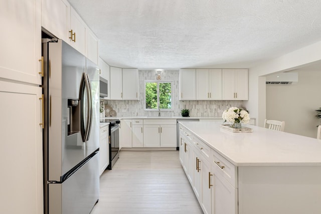 82260 Overseas Hwy, Islamorada, FL 33036 - kitchen featuring appliances with stainless steel finishes, light wood-style floors, a wall mounted AC, backsplash, and light countertops