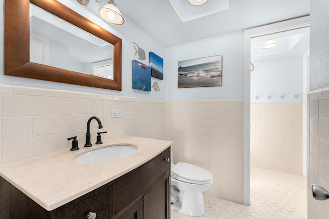 bathroom with tile patterned flooring, tile walls, vanity, a shower, and toilet