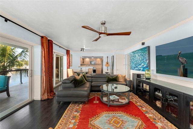 living room with dark hardwood / wood-style flooring, crown molding, and ceiling fan