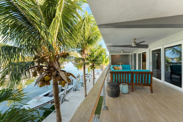 wooden terrace featuring outdoor lounge area, ceiling fan, and a water view