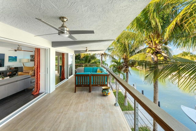 balcony with a water view, ceiling fan, and an outdoor hangout area