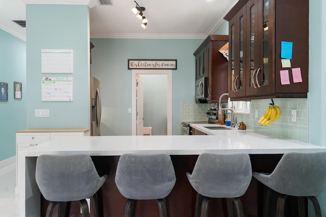 kitchen featuring ornamental molding, backsplash, appliances with stainless steel finishes, light countertops, and glass insert cabinets