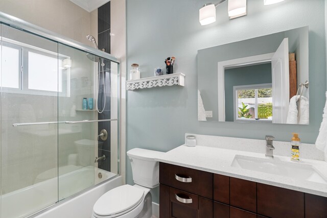 full bath with vanity, toilet, and shower / bath combination with glass door