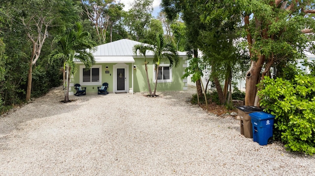 bungalow featuring stucco siding and metal roof