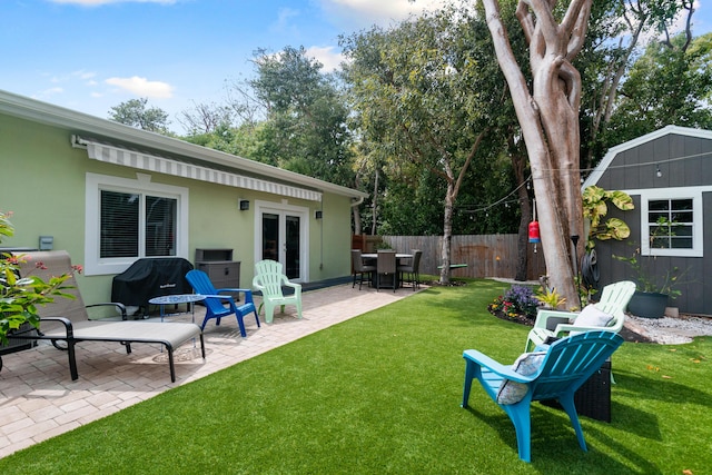 view of yard with an outbuilding, a shed, fence, french doors, and a patio area