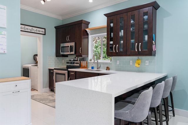 kitchen with a sink, dark brown cabinets, appliances with stainless steel finishes, and separate washer and dryer